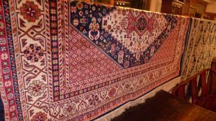 A Caucasian design carpet the dark blue ground with central medallions and repeating motifs in multi
