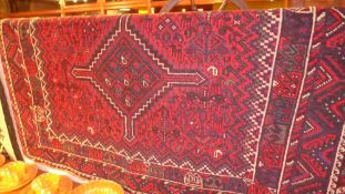A Persian rug with a triple pole medallion on a midnight blue and red field surrounded with two
