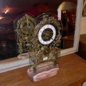 A brass skeleton clock on marble base with enamel dial