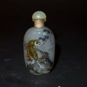 A Chinese reverse painted snuff bottle decorated with a landscape scene with tigers