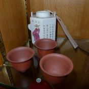 A Chinese porcelain teapot with calligraphy and figural decoration and three terracotta tea bowls