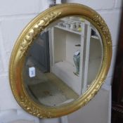 A gilded circular wall mirror with bevelled plate