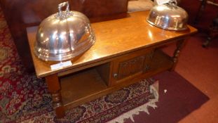 A Cotswold School style oak low table fitted with single linen fold panel door on turned supports
