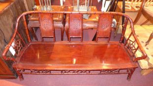 A Chinese rosewood bamboo style three seater settee with solid seat and star form decoration to