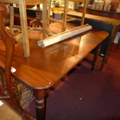 A Victorian mahogany extending dining table with one extra leaf and raised on turned supports