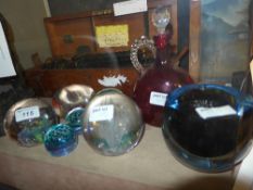 A collection of colour glass paperweight and a cranberry glass decanter
