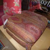 A pouffe upholstered in geometric fabric and two large cushions