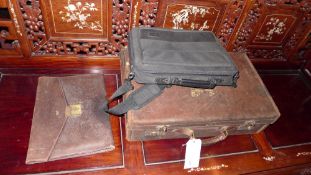 An old brown leather suitcase, together with a brown leather document case, and a laptop bag