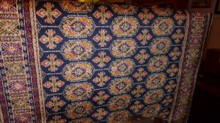 A Persian Bokhara style runner the dark blue ground with repeating gold motifs in a triple border