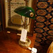 A brass desk lamp with opaque green glass shade
