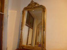 A wall mirror with bevelled arched plate within ornate gilt frame with leafy surmount