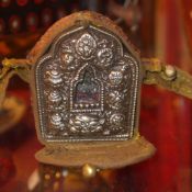 A Tibetan silk belt with white metal buckle having decoration in relief