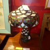 A Tiffany style table lamp with stained leaded glass shade and illuminating base