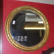 A gilded circular wall mirror with bevelled plate