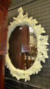 A cream painted acorn relief oval bevelled plated wall mirror
