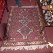 A Persian hand knotted rug the rouge field having three pendant medallions and multicoloured motifs