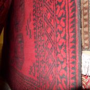 A hand made Afghan carpet the dark red ground with repeating blade motifs in a multi border