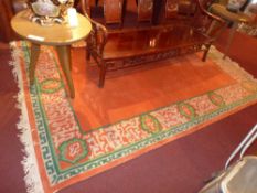 A large contemporary rug the orange ground within green and beige border with repeating motifs