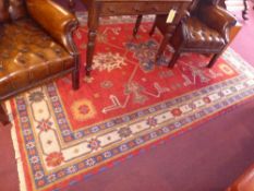 A hand knotted Kazak carpet the beige ground decorated with floral blue and red motifs in multi