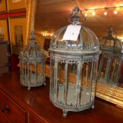 A pair of wrought iron and glazed storm lanterns of graduating size