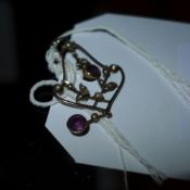 A yellow metal pendant inset with seed pearls and amythyst