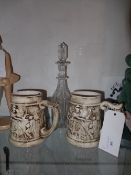 A Victorian cut glass decanter with etched detail and a pair of Continental pottery tankards (3)