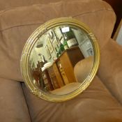 A gilded circular wall mirror with bevelled plate and a mahogany mirror