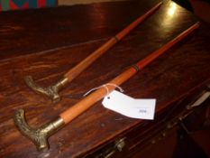 A pair of walking sticks with brass handles and a section for hidden drinks