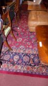 A large Persian style carpet the dark red field having extensive floral decoration allover in a