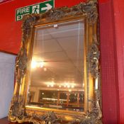 A wall mirror the rectangular bevelled plate within ornate heavy gilt frame