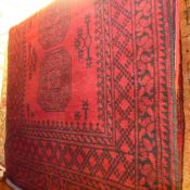 A hand knotted Afghan rug the red field with repeating black motifs