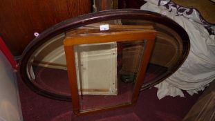 An oval looking glass with bevelled plate and an oak framed mirror