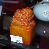 A Chinese amber coloured soapstone seal surmounted by a carved Kylin