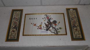 A pair of glazed and framed Chinese silk embroidered panels of birds in trees and a similar of an