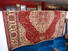 A Kum style carpet the gold and rouge field having allover foliate decoration in a multiborder