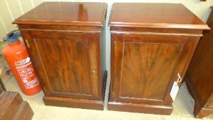 A pair of mahogany bedside cupboards with fielded panel doors on plinth base