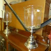 A pair of glass and chromium pedestal storm lanterns