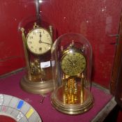 Two brass clocks under glass domes