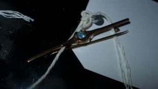 A 9ct gold pin with inset blue stone