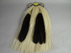 A horsehair and leather sporran with white metal border bearing thistle and phoenix insignia