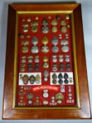 A collection of Royal Welsh Fusiliers badges and buttons in oak frame with red felt backdrop