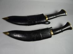 A pair of military-style Nepalese kukries in black leather and brass-tipped scabbards
