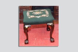 A tapestry topped footstool on carved knee and ball and claw supports