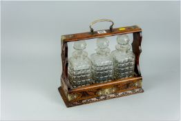 An oak three bottle tantalus having carved decoration, EPNS decorative mounts and escutcheon with
