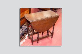 An oak barley twist gate leg table, an ebonized two door glazed bookcase, a mahogany three shelf