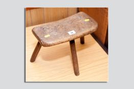 An early fruitwood country stool on three legs, 9.75 x 12.5 ins (25 x 32 cms)