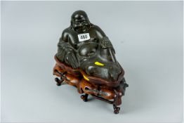 A cast bronze figure of an Oriental deity in a reclining position, semi-clad with a robe depicting