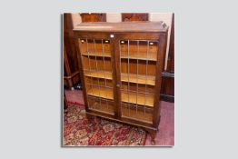 An oak bookcase having twin leaded glass doors on pad foot supports