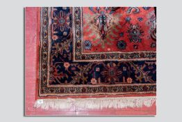 A rust and cobalt blue ground patterned tassel edged carpet, approximately 3 x 2 yards