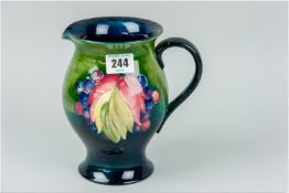 A Moorcroft leaf and berry patterned jug, cobalt coloured interior, green and cobalt coloured